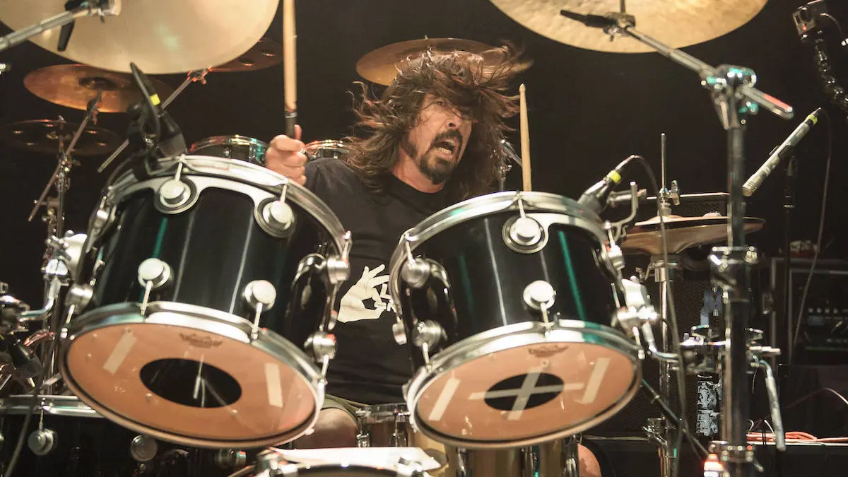 Dave Grohl playing a black drum set.